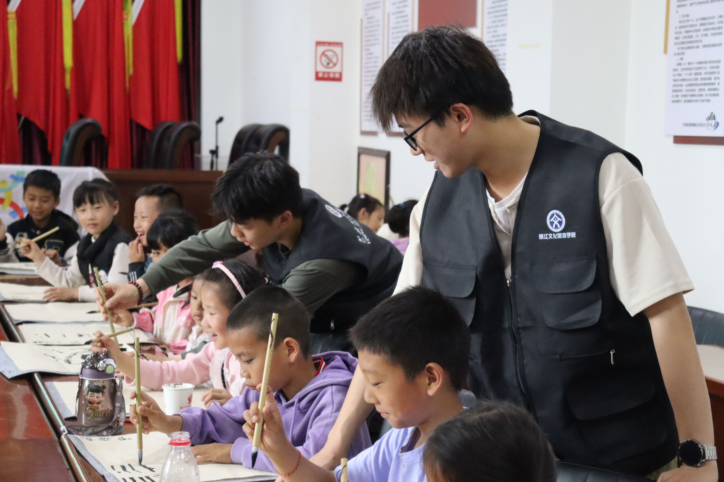 7.丽江文化旅游学院艺宁服务团实践队成员在教小学生书写毛笔字.jpg
