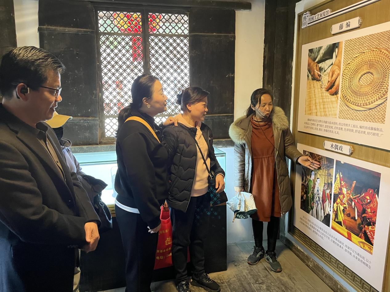 图为当地讲解员林梅生给党员教师讲解地方木偶戏的历史