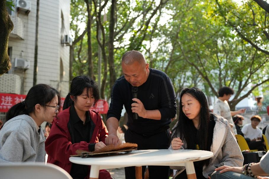 图为魏祖选指导同学制作蓑衣。