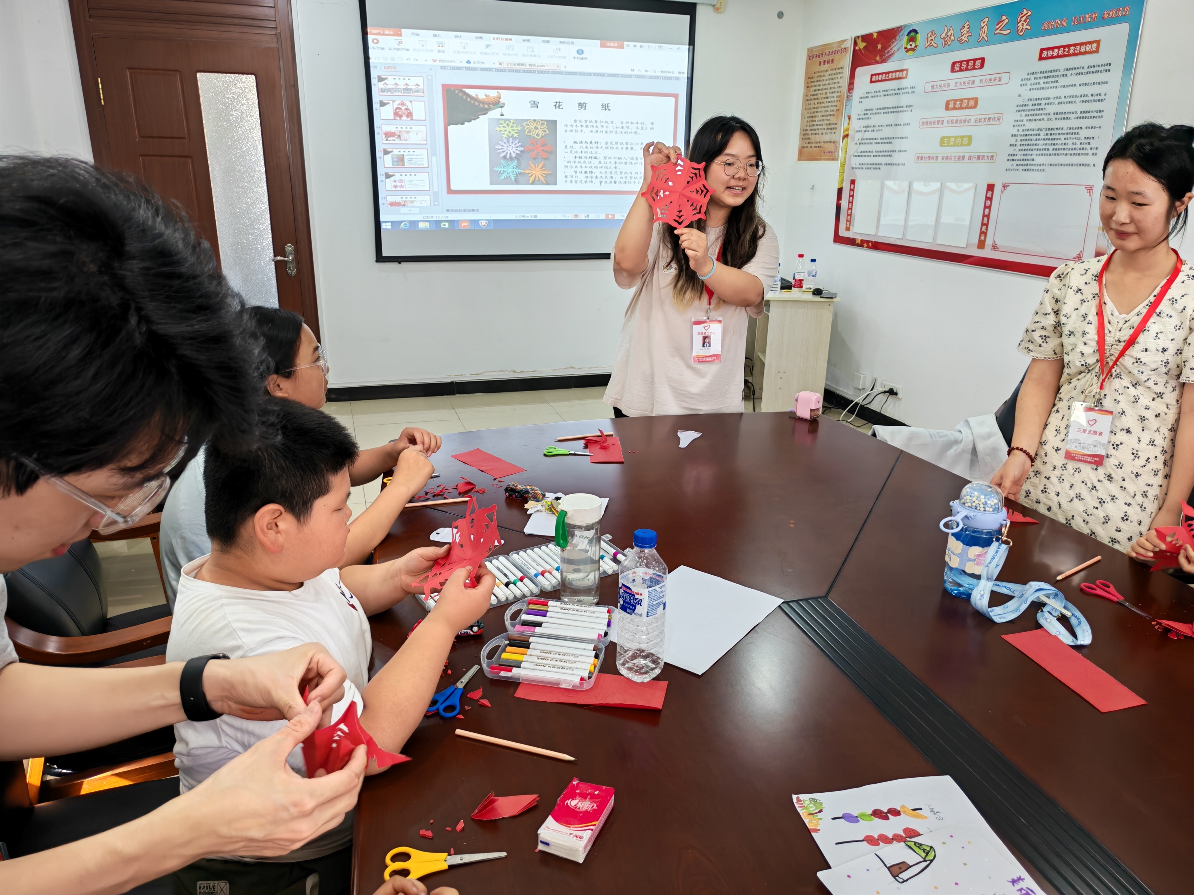 图9：7月7日非遗剪纸技艺教学课堂志愿者和儿童一起剪纸